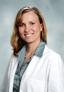 Dr. Skuben in white doctor's coat, blond hair and bright smile.